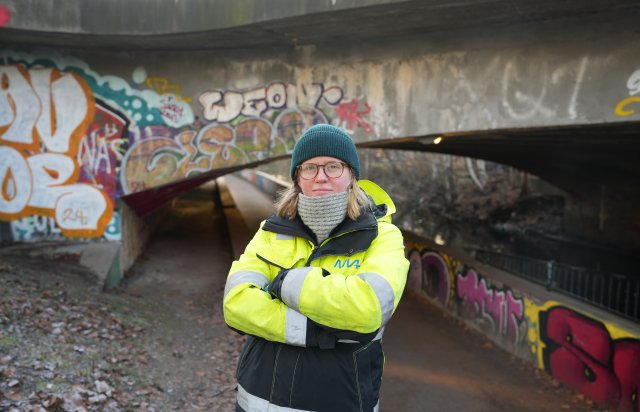 person i refleksjakke foran en bro med grafitti