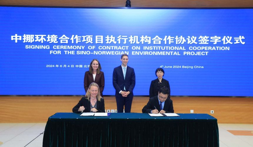 Signing of contract in front of screen with name of project in Chinese and English