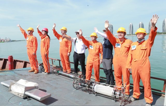 SINOPLAST workers in orange jumpsuits waving